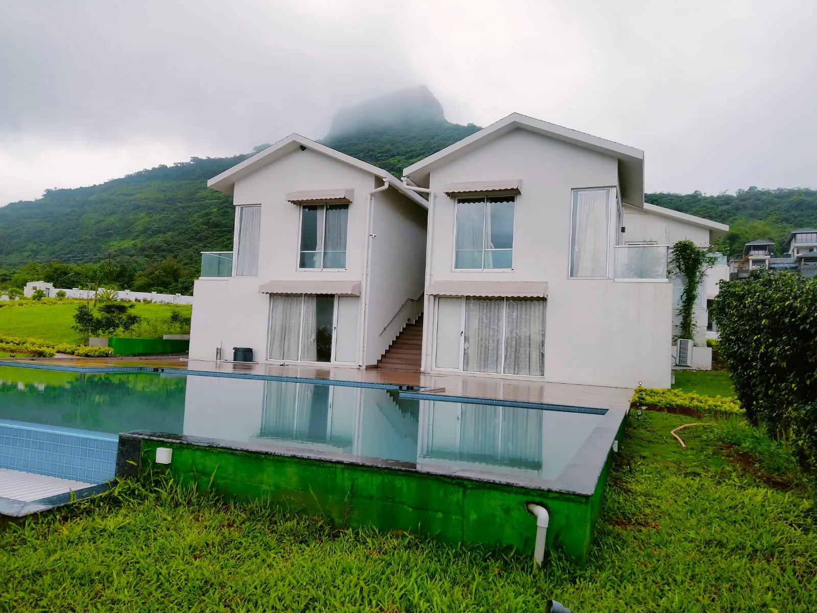 The villa and pool in monsoon mist, Tikona fort in cloud behind